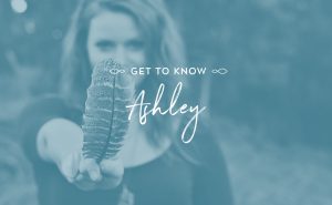 Image of empowered woman leader holding feather toward camera with overlaid text "get to know Ashley"